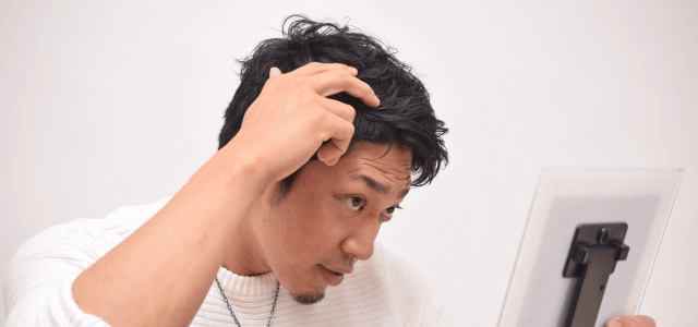 手鏡で髪をチェックする男性